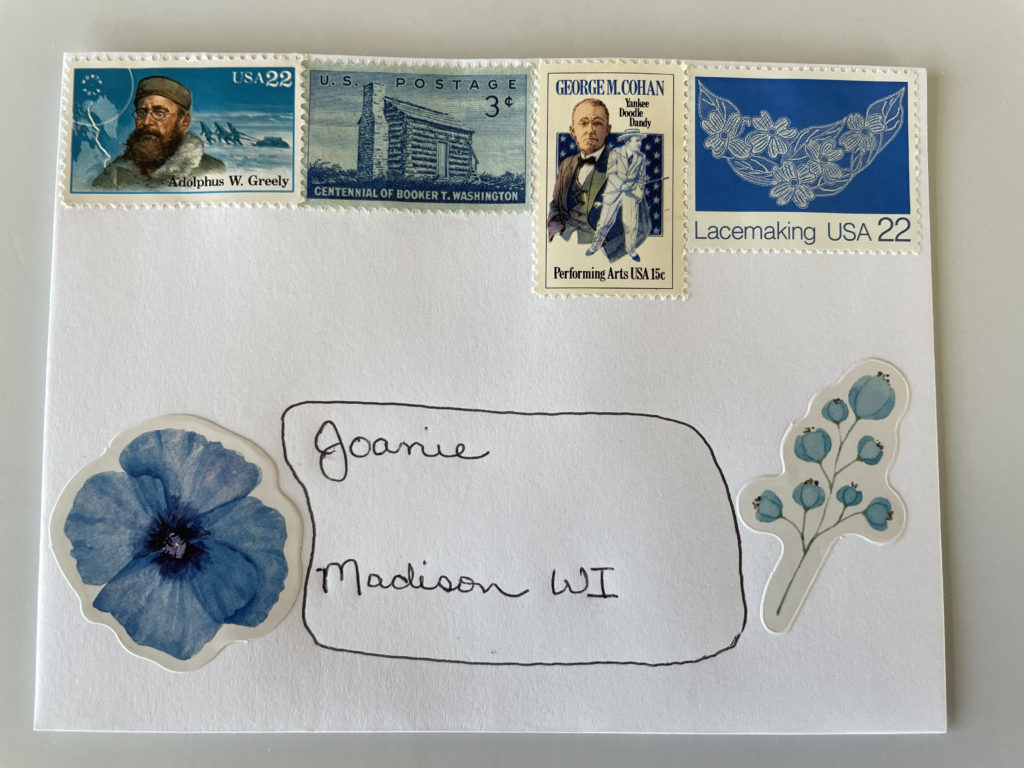 An addressed envelope decorated with blue flower stickers and blue vintage stamps